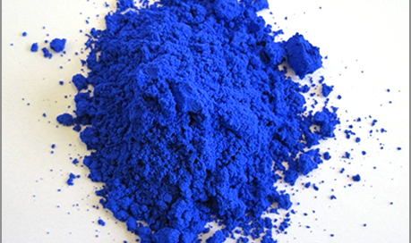 Bright royal blue pigment powder mounded on a white surface.