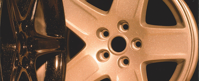 Copper and bronze five-spoke automotive wheel hubcap against a dark background.