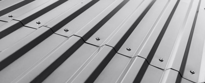 Close-up of dark charcoal corrugated metal roofing panels with visible fasteners, showing black pigment in industrial use.