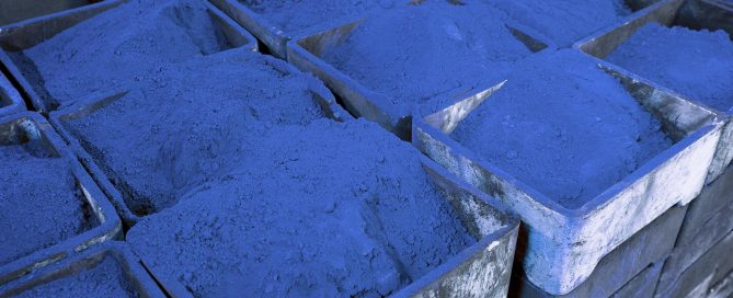 Rows of blue pigment-filled containers showing varying shades of cobalt and navy blue in a tightly packed grid.