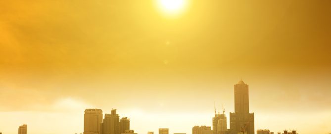 Dense urban skyline bathed in warm golden sunlight with high-rise buildings silhouetted against the glowing sky.