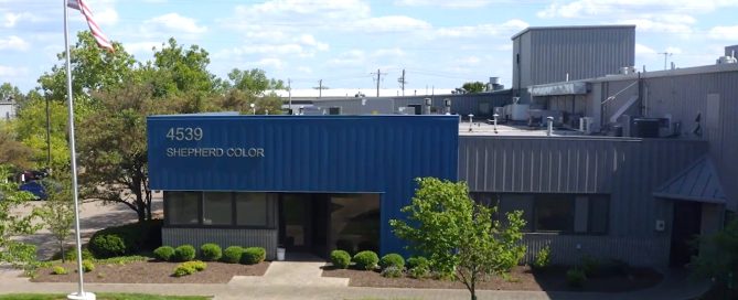 Exterior of Shepherd Color Company building with blue and gray metal facade and company signage.