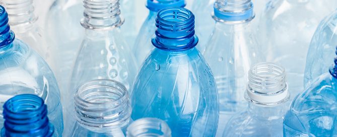 Clear plastic water bottles with blue caps arranged tightly together.