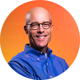 Professional headshot of a man wearing glasses and a blue shirt against an orange circular background.